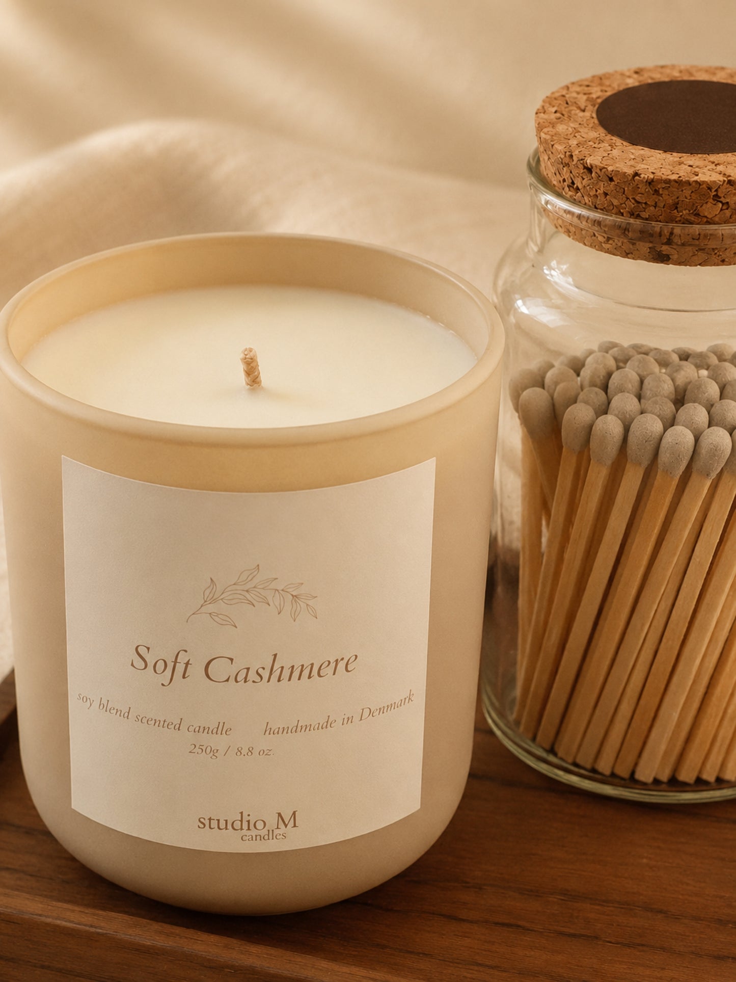 Detail-Aufnahme von Duftkerze "Soft Cashmere" und Streichholzglas auf Holztablett