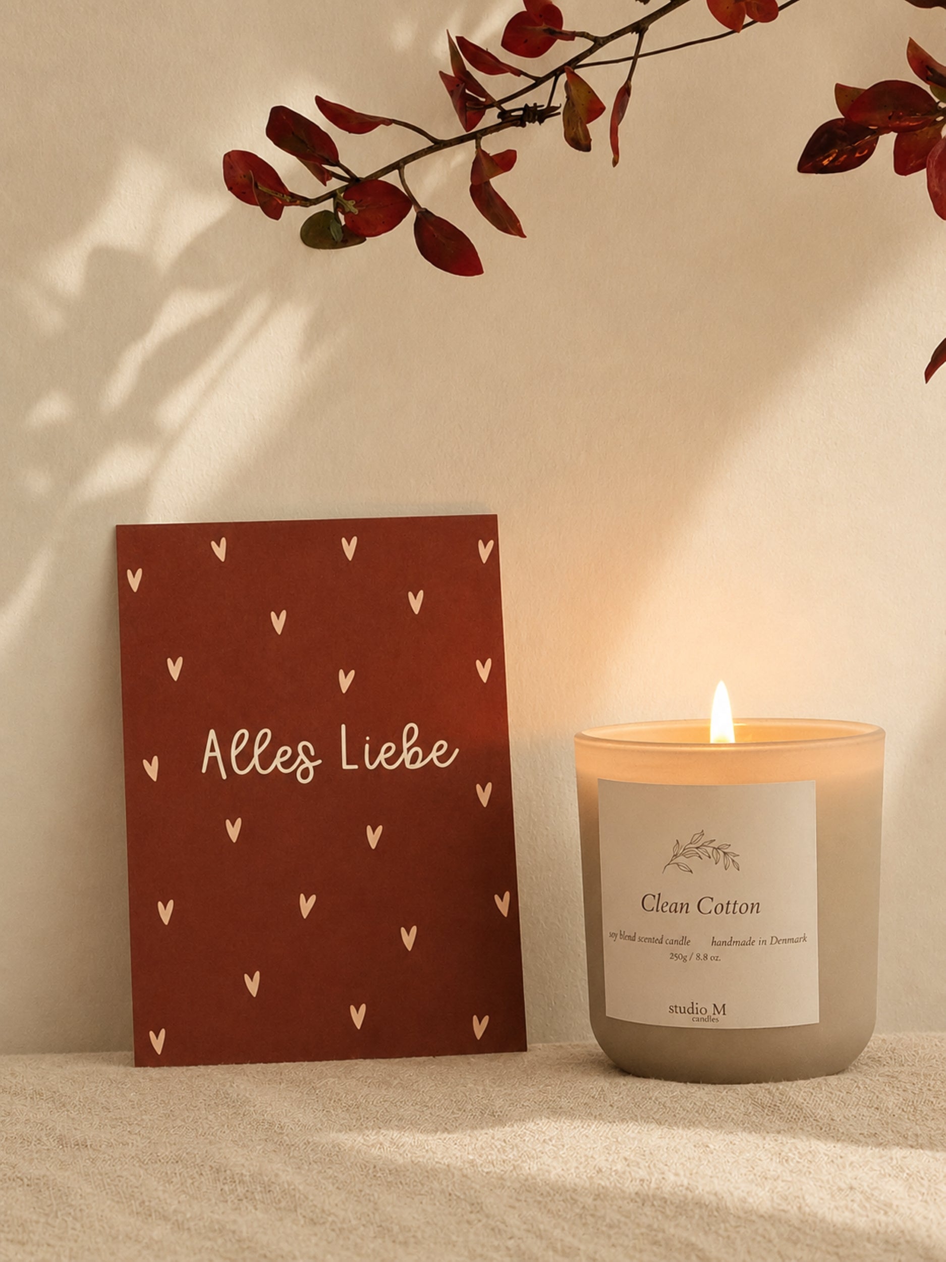Postkarte "Alles Liebe" neben einer brennenden Duftkerze