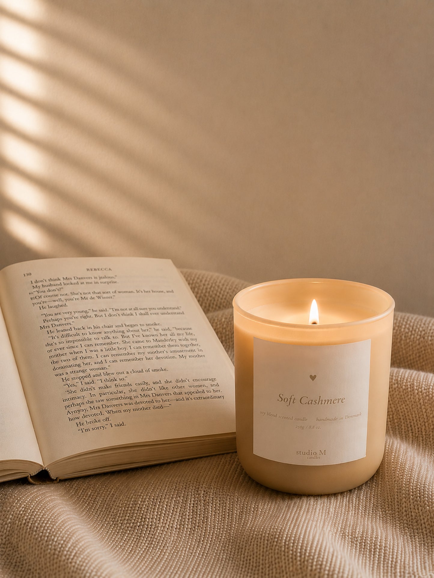 Brennende Duftkerze Soft Cashmere neben geöffnetem Buch