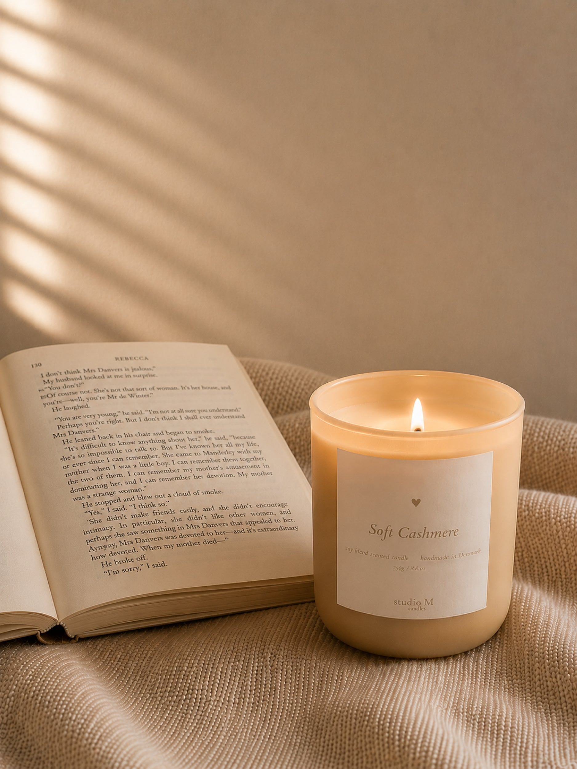 Brennende Duftkerze Soft Cashmere neben geöffnetem Buch