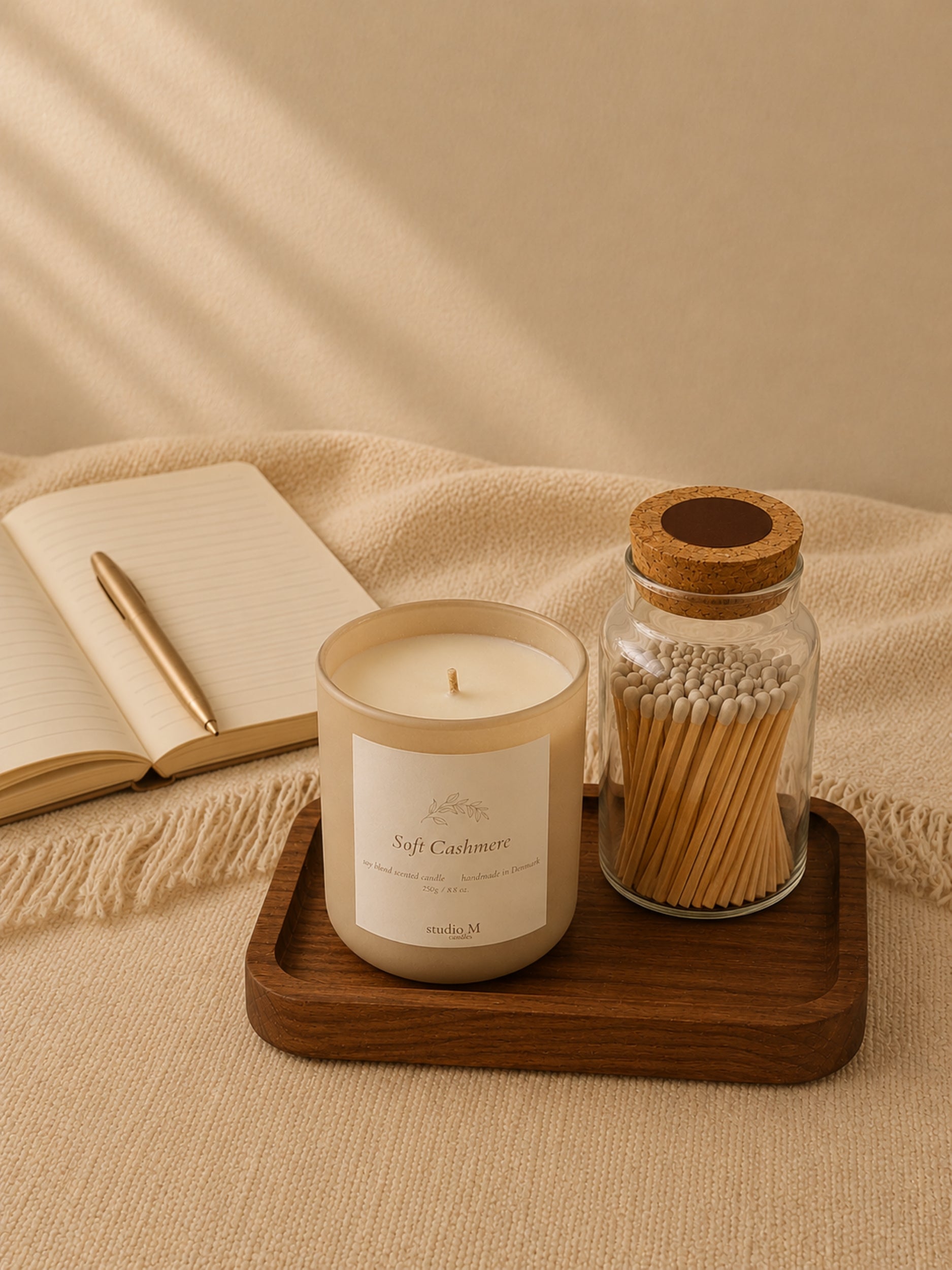 Duftkerze "Soft Cashmere" mit Streichholzglas auf Tablett neben einem geöffneten Notizbuch